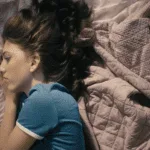 Teen girl scrolling on her phone how AI-generated porn is harming teens